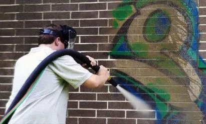 Abrasive cleaning of graffiti on a brick wall